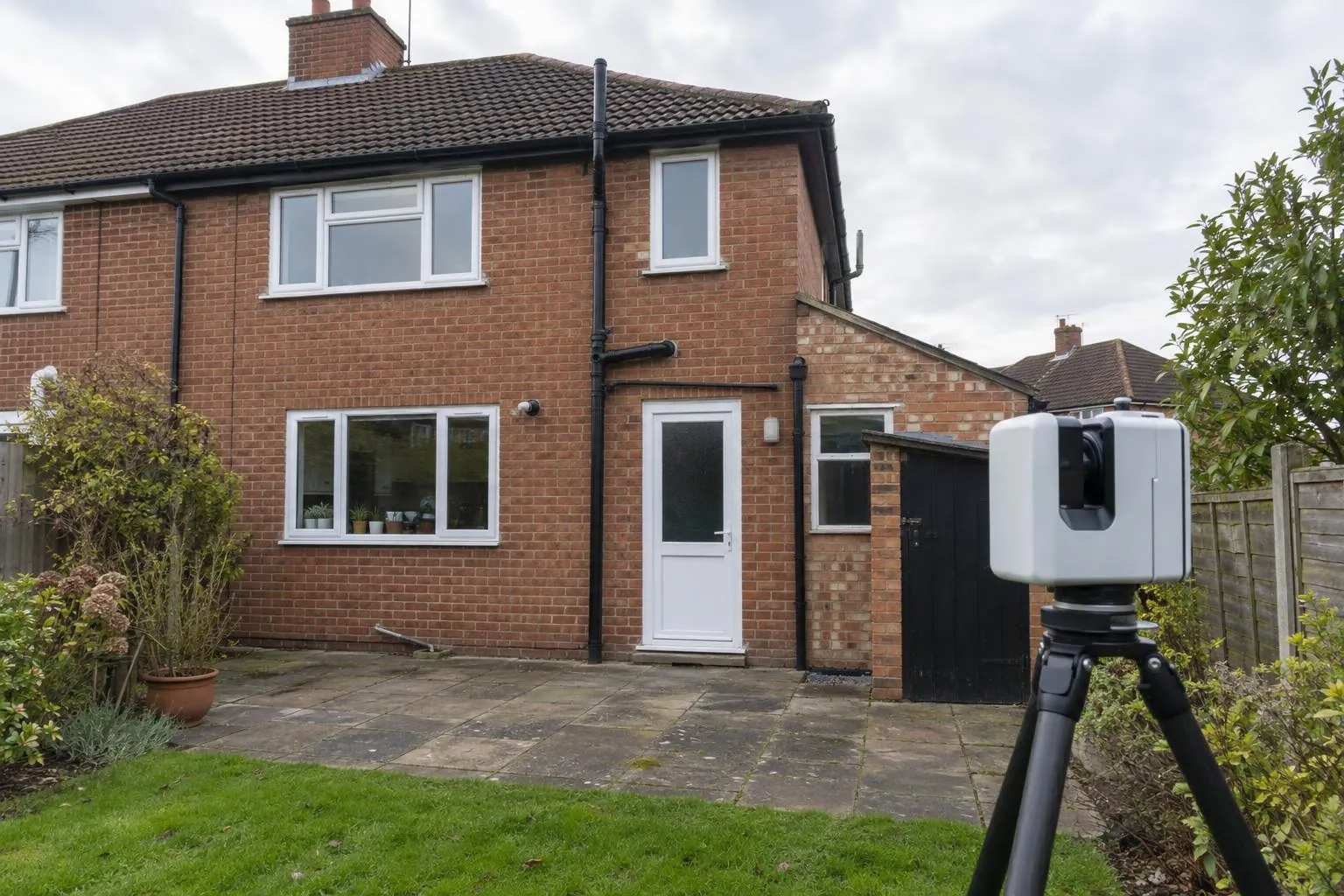 Laser scanner set up to survey the rear elevation of a 1930s semi-detached house before an extension